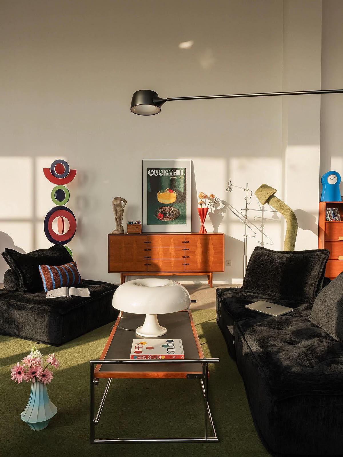 Sunlit retro living room with black seating, walnut furniture and a chrome table