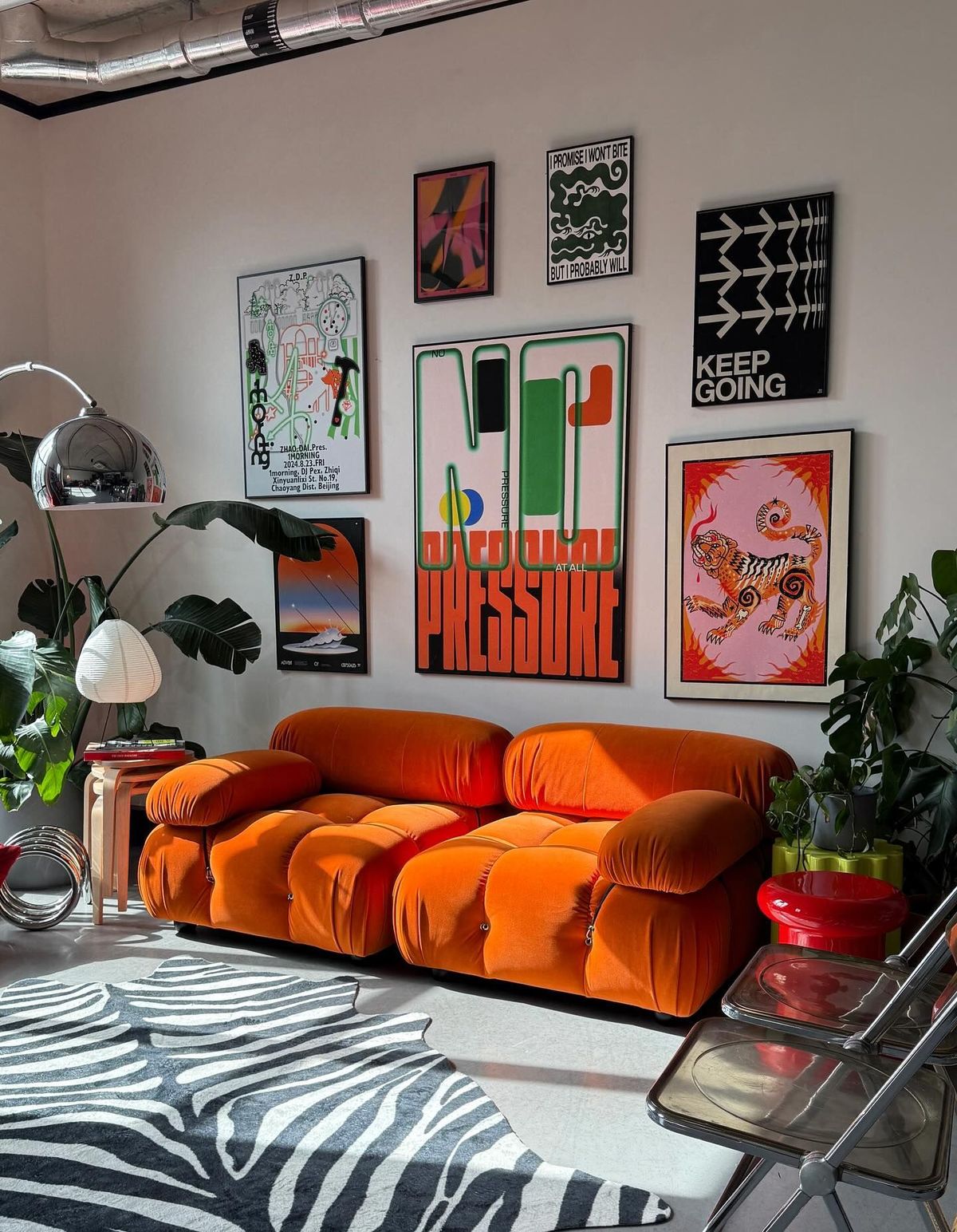 Orange sofa, zebra rug, chrome details and houseplants in a modern retro room