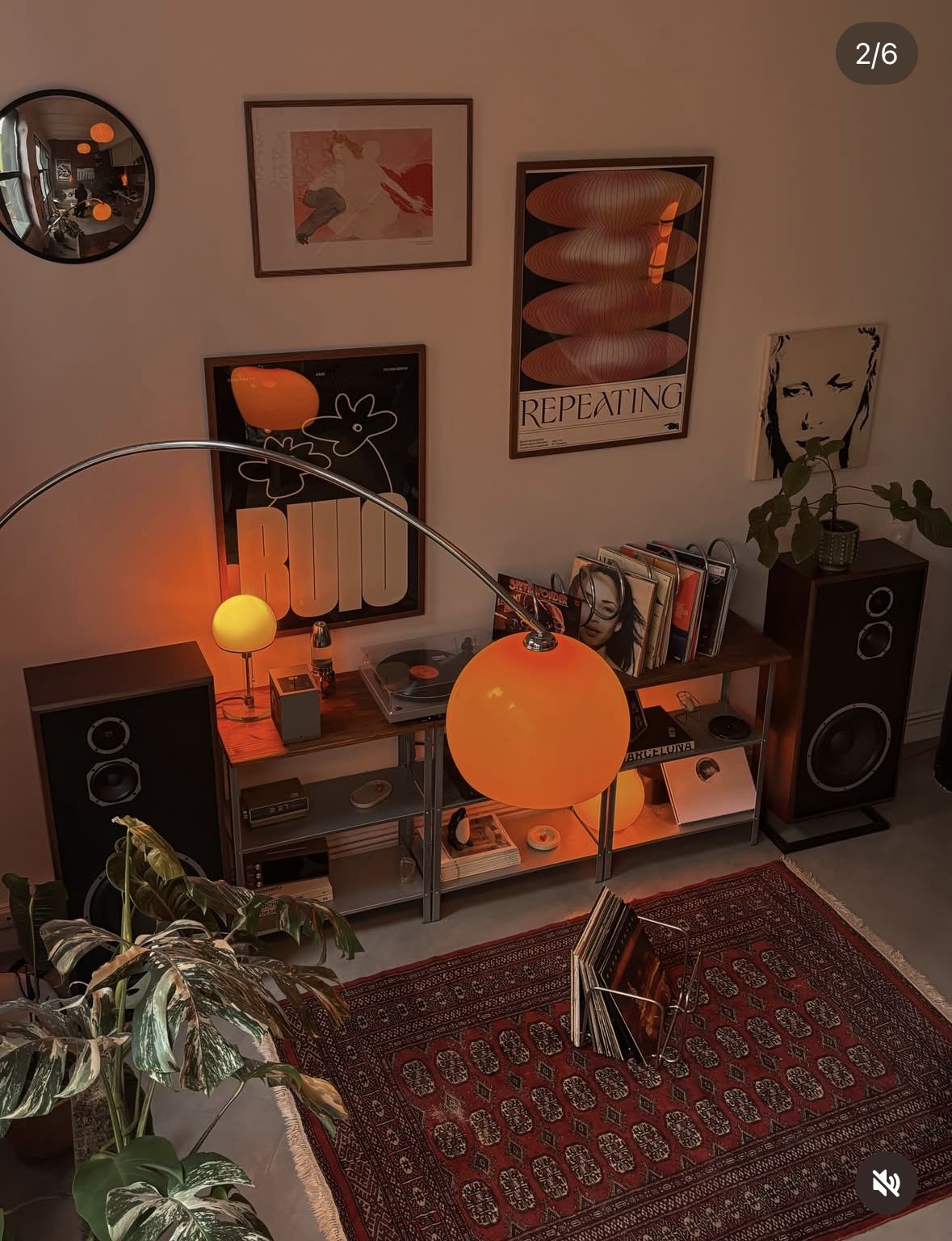 A warm orange lamp, vinyl records and framed art in a retro music corner