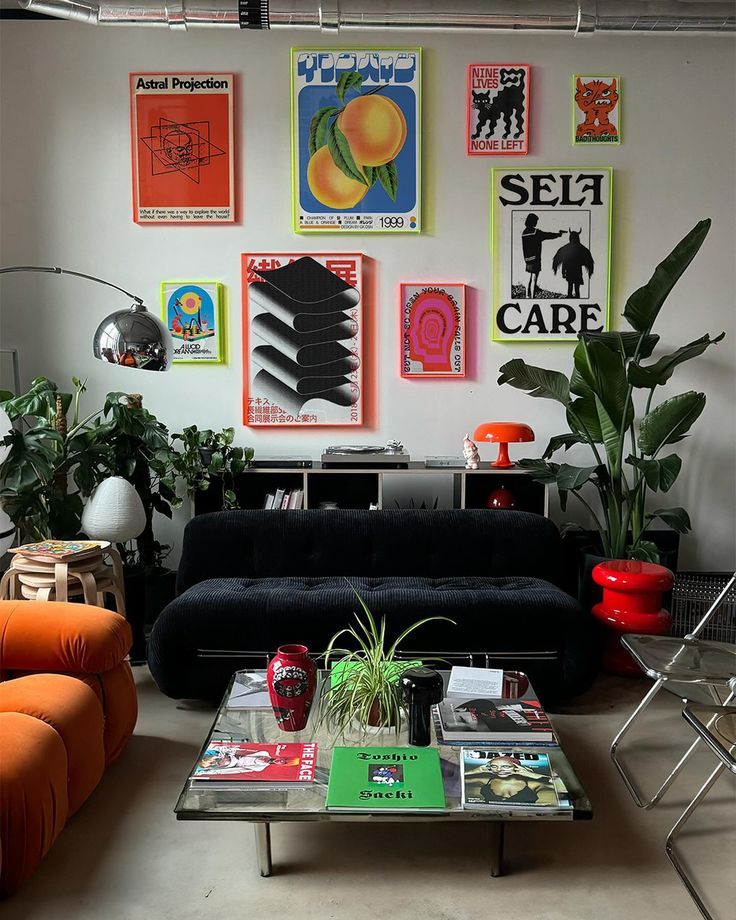 Eclectic living room with poster art, plants, a black sofa, and an orange chair